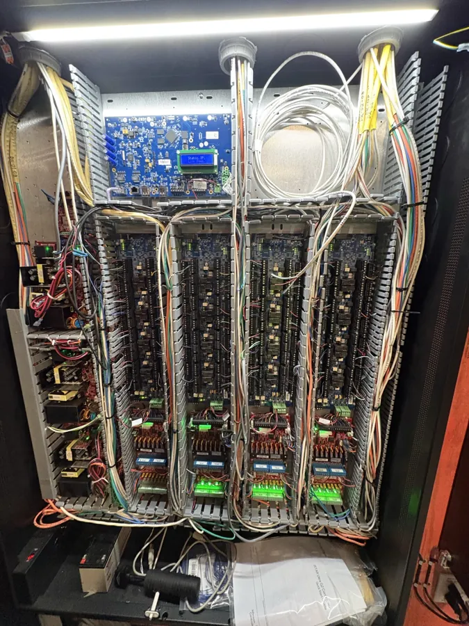 Open security control cabinet with routed cables and control boards, photographed at an FM Tech airport terminal project