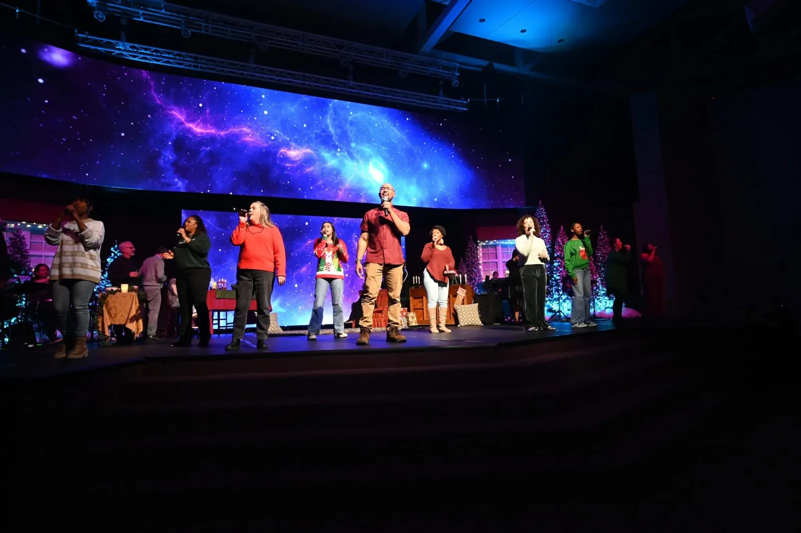 Worship team singing on a church stage in front of a wide LED video wall showing a nebula image, from an FM Tech LED video wall project