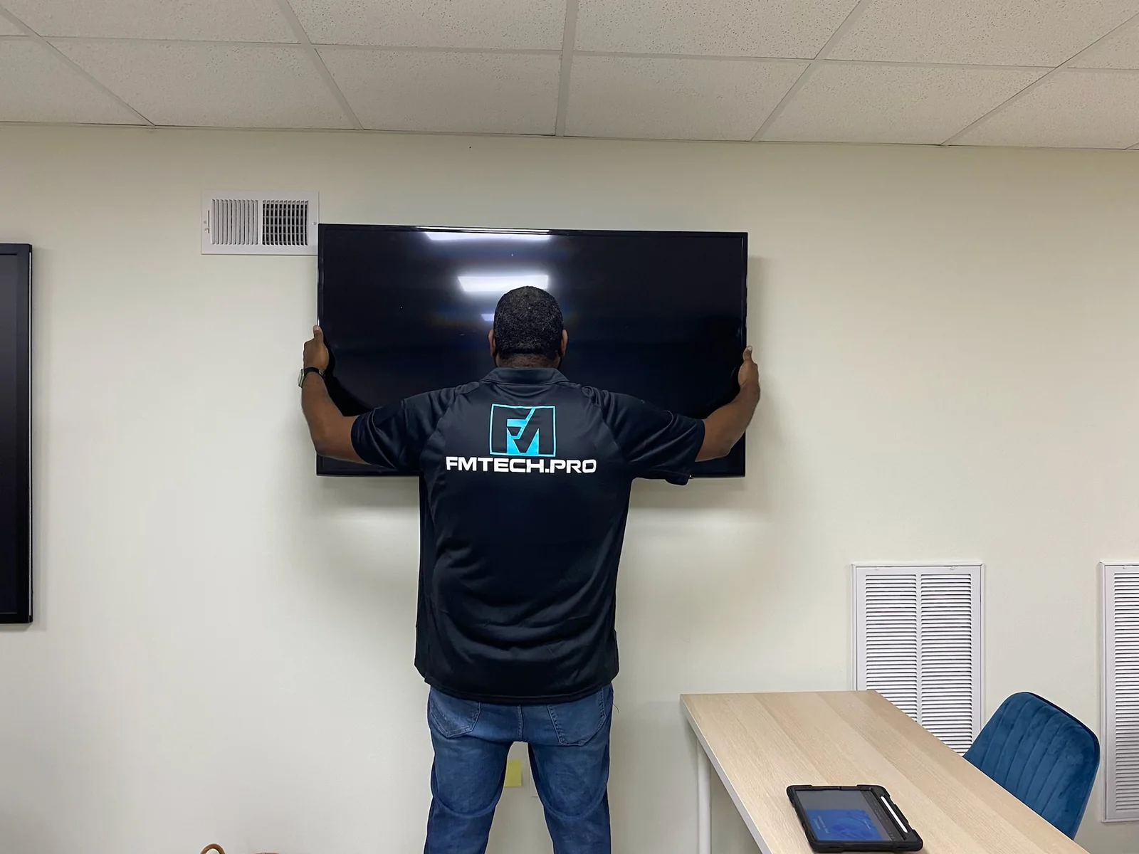 FM Tech owner mounting a television display in a commercial facility