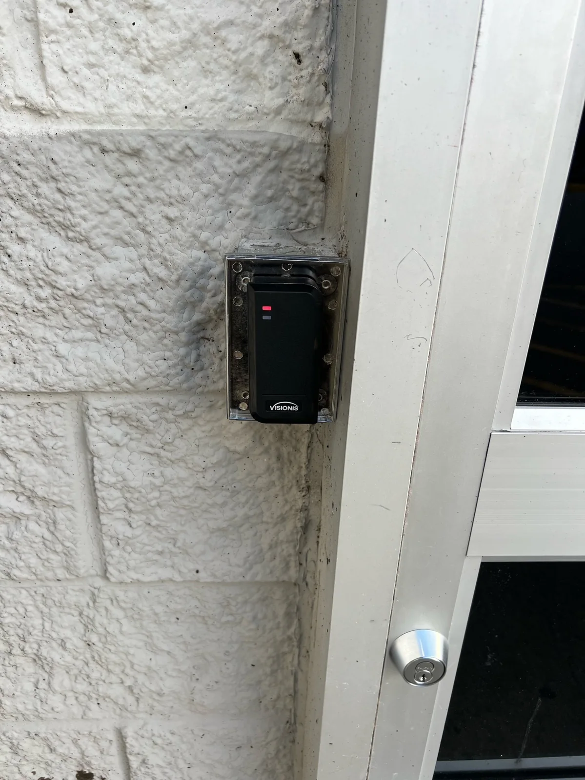Electronic access control reader installed beside an exterior building entrance.