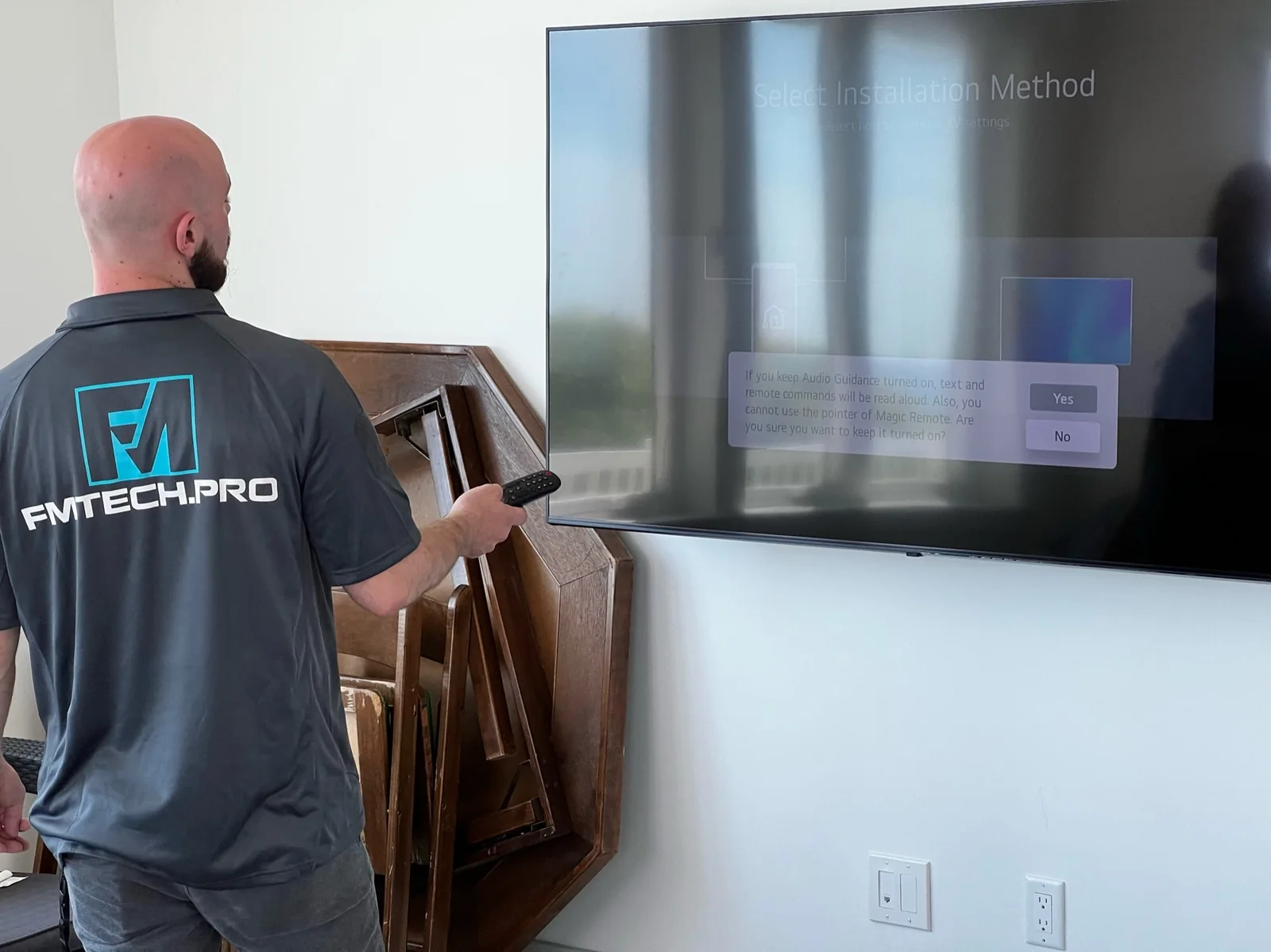 FM Tech technician mounting and programming a commercial television display