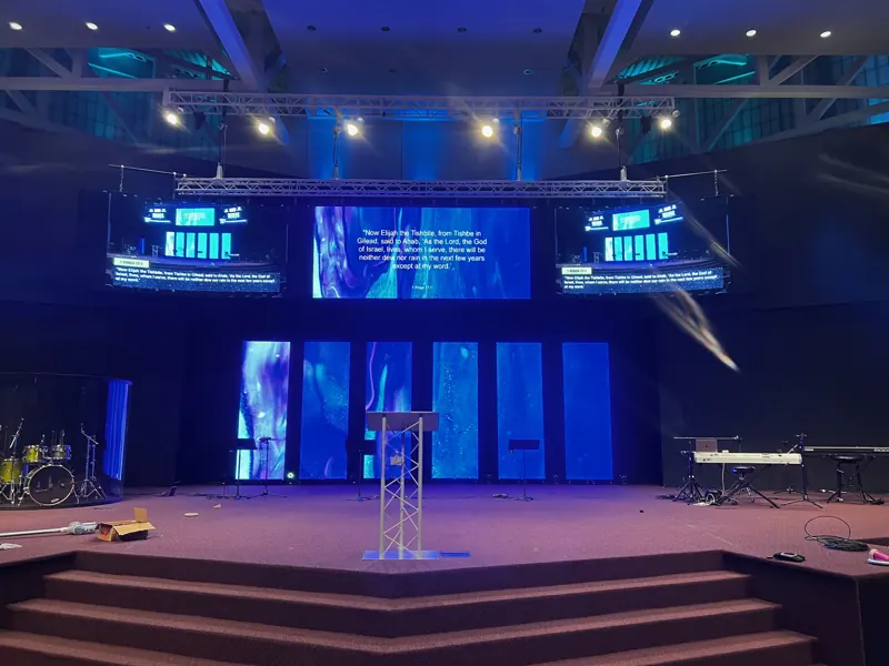 Church stage with a lectern and several LED display panels showing video and text